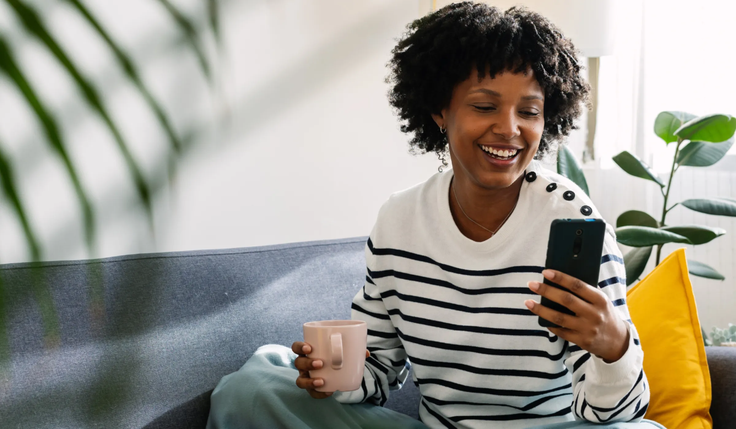 Fröhliche Frau auf dem Sofa mit dem Smartphone